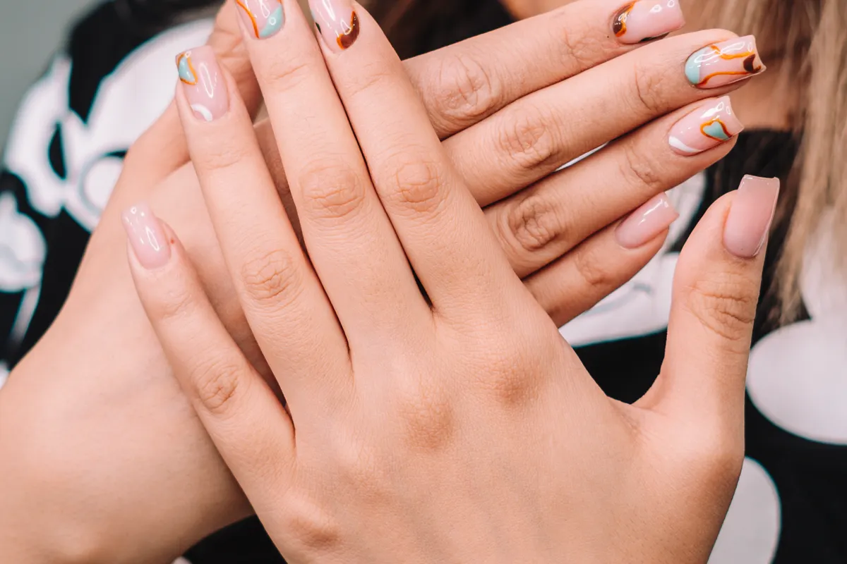 Finished pale pink manicure held in soft light